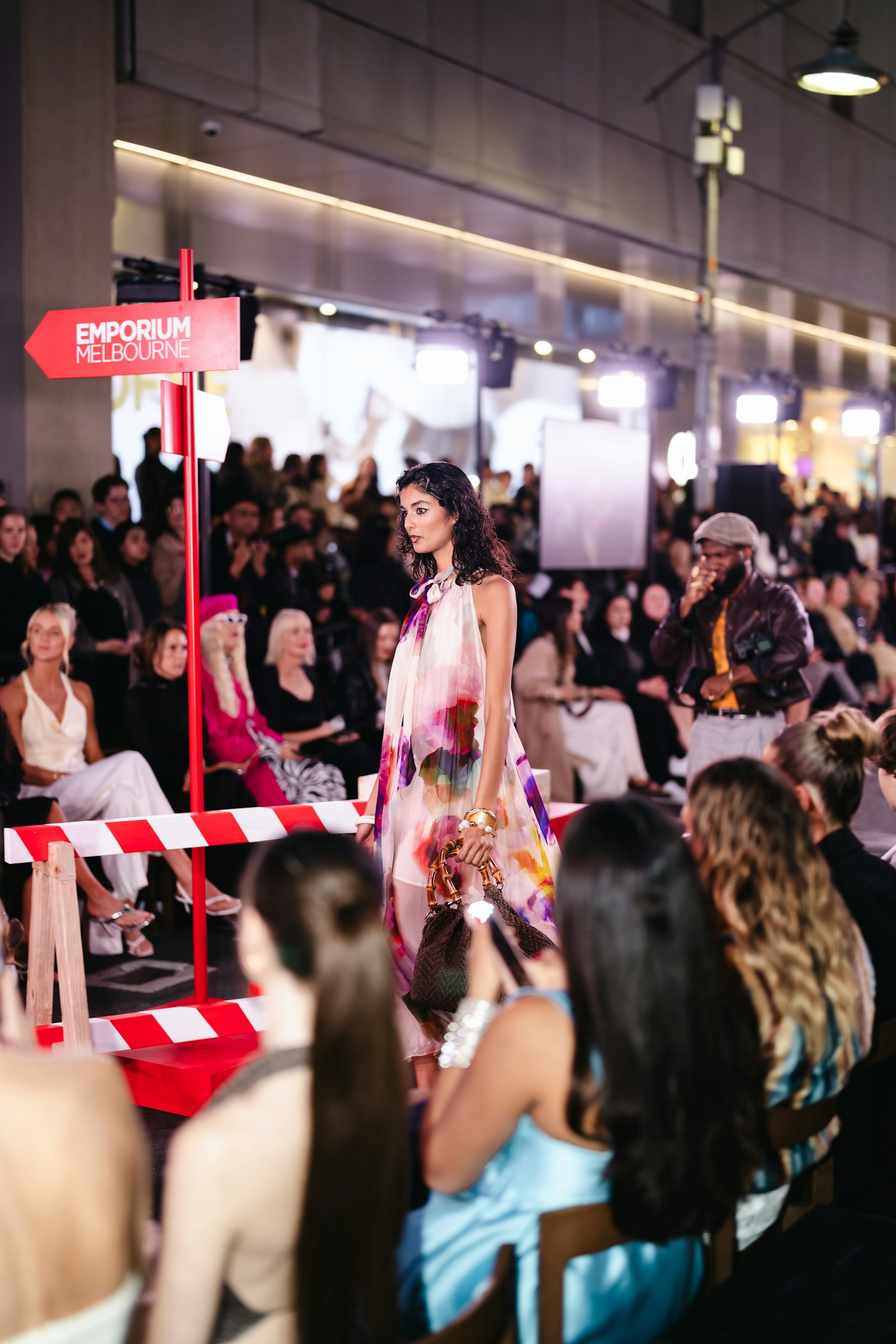 Model walking the runway at a fashion show with audience watching